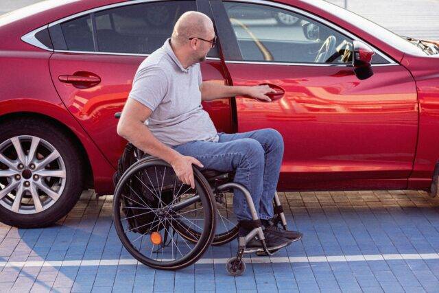 Man in wheelchair getting into car driving with a disability