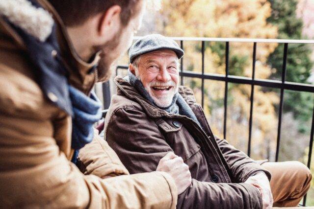 Man talking to elderly man, smiling