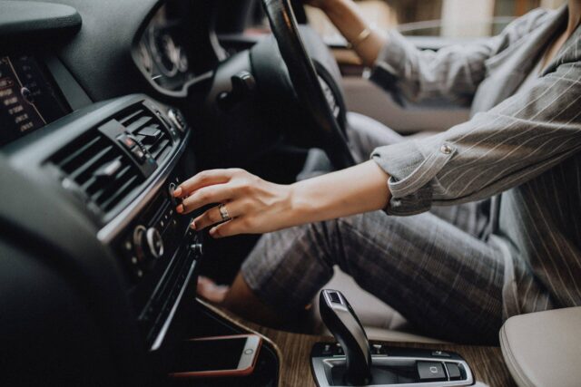 woman driving car with hand over dashboard