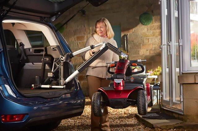 Woman standing next to her car boot and mobility scooter