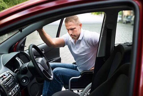 Man in wheelchair getting into car