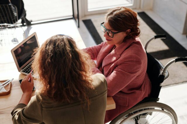 Wheelchair users sitting around a laptop conducting an online mobility assessment