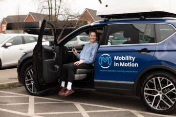 Robyn Love smiling sat on swivel seat in the front passenger side of Mobility in Motion demo car