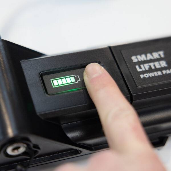 a finger pressing the button to show the charge level on the Battery Pack. The lights are illuminated, showing it is fully charged.