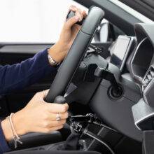 A side view of the steering wheel in an adapted car with mechanical push/pull hand controls next to the steering wheel and a steering ball