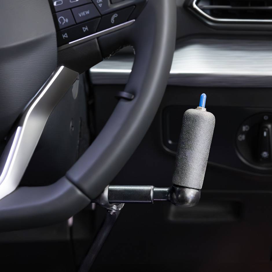 the handle of push pull mechanical hand controls next to the steering wheel in a car. The handle has a switch on top to control the indicators
