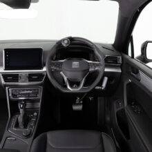 A driver's seat view of the wheel in an adapted car with mechanical push/pull hand controls next to the steering wheel and a steering ball