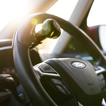 A driver's seat view of the steering wheel in a car with a steering Ball on the steering wheel