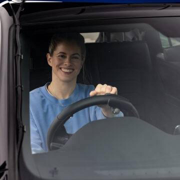Paralympian Robyn Love sat in the driver's seat of a car holding a Steering Ball