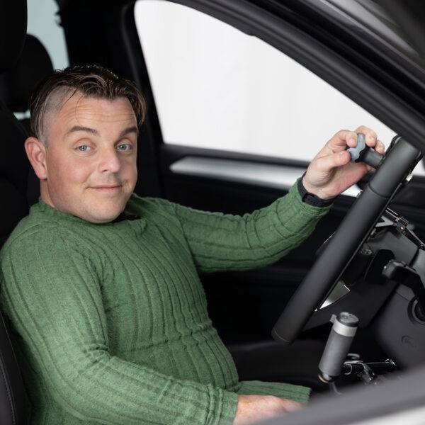 Marcus - The Disabled Reviewer sat in the driver's seat of a car holding a Steering Ball