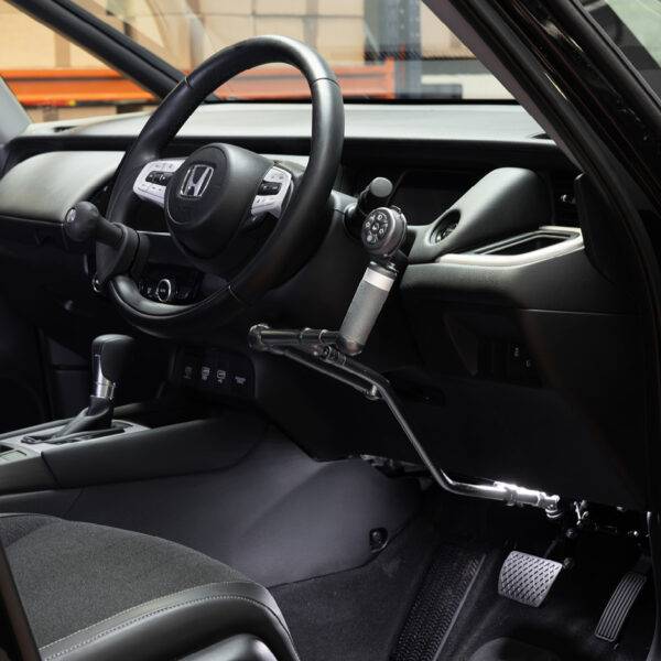 The steering wheel in a car with mechanical push/pull hand controls next to the steering wheel and a remote control keypad above them