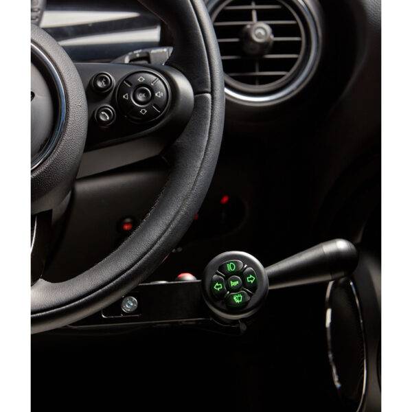 A driver's seat view of the steering wheel in a car with mechanical push/pull hand controls next to the steering wheel and a remote control keypad above them
