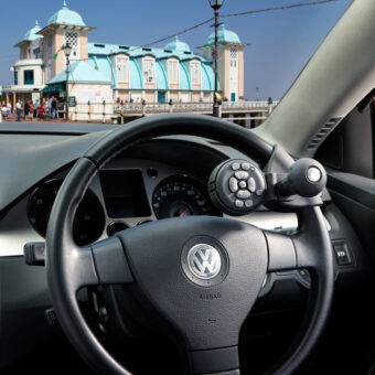 A driver's seat view of the steering wheel in a car with a steering Ball on the steering wheel with a remote control keypad