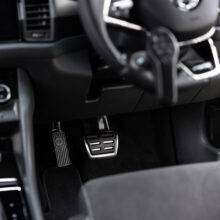 A driver's seat view of a car interior. There is a steering aid on the steering whee. In the footwell the accelerator is folded up and out of the way, a second accelerator pedal has been folded down to the left of the accelerator pedal.