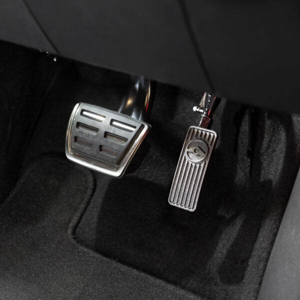 A driver's seat view of a car interior. In the footwell the accelerator has a hinge visible above it, allowing it to be folded up and out of the way