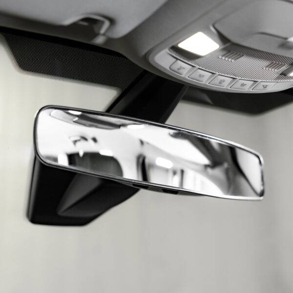 The interior of a car showing a panoramic rear view mirror attached over the top of the car's original mirror. It is wider than a traditional rear view mirror.