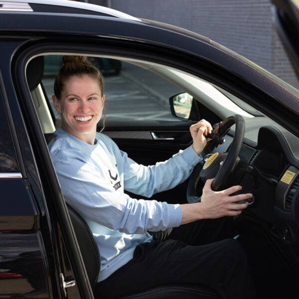 Paralympian Robyn Love sat in the driver's seat of a car holding a Steering Ball and the Hand Controls