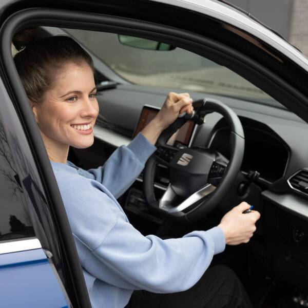 Paralympian Robyn Love sat in the driver's seat of a car holding a Steering Ball and the Hand Controls