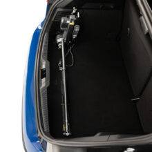 The boot of a Ford Focus with the Brig-Ayd 40kg Boot Hoist, a tall, slender, folding and collapsible hoist arm with a green lifting cord and clip for multiple types of mobility device. It is folded and collapsed down into its transporting position taking up very little boot space.