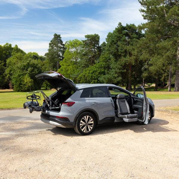 The open boot of an EV car with the Autochair Smart Lifter LC Boot Hoist lifting a mobility scooter and a Turny Evo Swivel seat turned out and lowered down from the driver's seat.