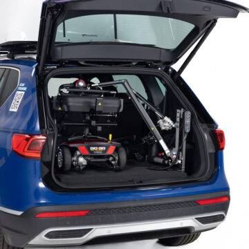 The open boot of a car showing a pavement scooter with the smart scooter seat loaded into the boot by the Autochair Smart Lifter LC compact Boot Hoist.