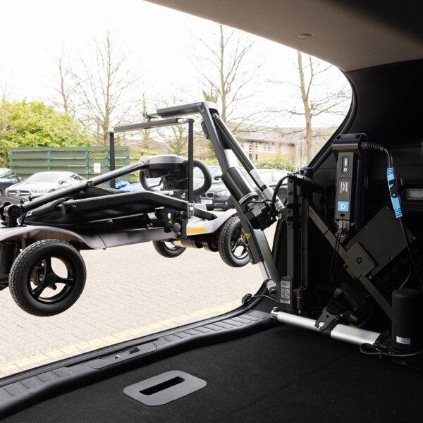 A view looking out the back of a car with its boot open. On the side of the boot is the Autochair Smart Lifter LC Boot Hoist holding up a scooter. The Smart Lifter Power Pack is attached to the frame of the boot hoist.