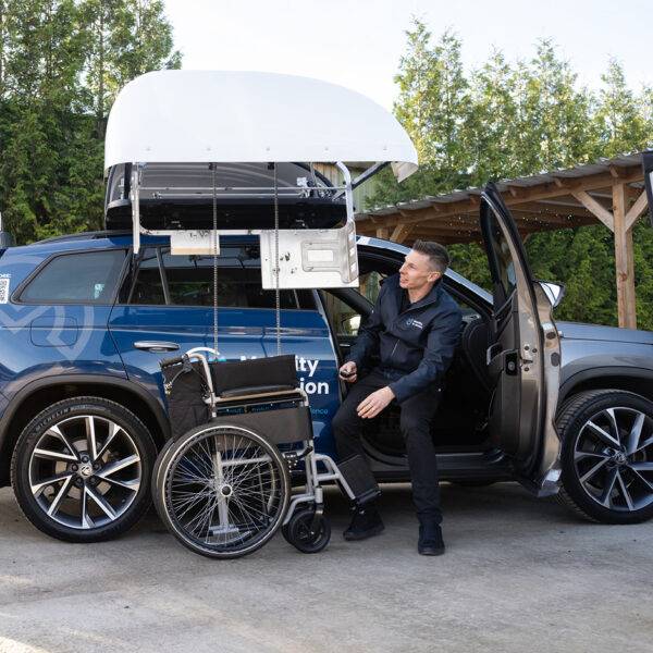 A Mobility in Motion assessor lifting a centre folding wheelchair into the roof box of the car with the BraunAbility Chair Topper.