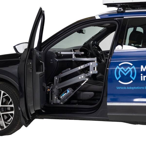 The open passenger door of a car reveals the lifting arm of the Autochair Milford Person Lift, a smart grey person hoist with a blue sling, to lift occupants safely into the original seat of the car.