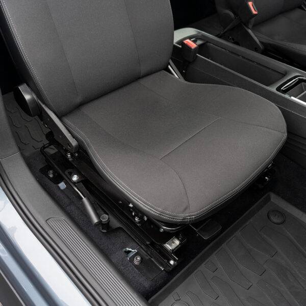 A swivel seat in the driving position of the driver's seat inside the car. The manual handle to turn the seat is visible to the left of the seat.