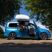 A VW Caddy with a BraunAbility Chair Topper, lowering a folding wheelchair down to the driver's seat, where a Turny Low swivel seat has turned the seat our of the car to bring the driver closer to the wheelchair for an easier transfer