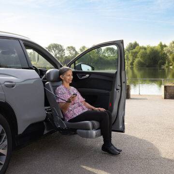 A woman sat on the Turny Evo swivel seat has turned the driver's seat out of the car and lowered it down to bring her to an ideal height for getting in and out of the vehicle.