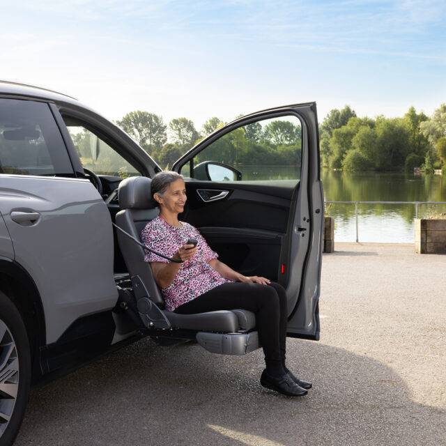 A woman sat on the Turny Evo swivel seat has turned the driver's seat out of the car and lowered it down to bring her to an ideal height for getting in and out of the vehicle.