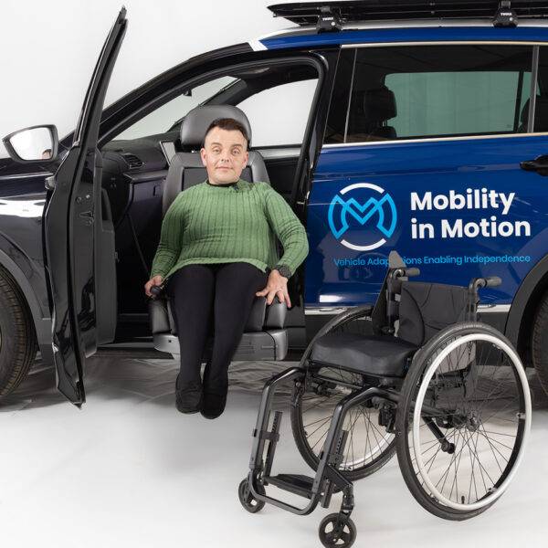 Marcus - The Disabled Reviewer sat in a swivel seat which is turned to face out of a car next to his wheelchair