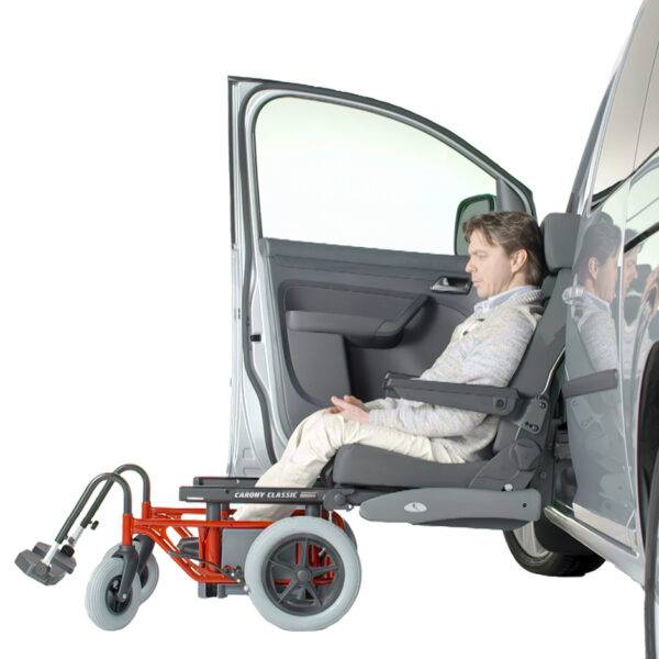 A man sits in a swivel seat that has turned out of the passenger's seat and lowered outside of the car. The passenger's seat has turned out of the car and lowered down to a height to allow the seat to slide off the swivel mechanism and onto a waiting set of wheels that will turn the car chair into a wheelchair.