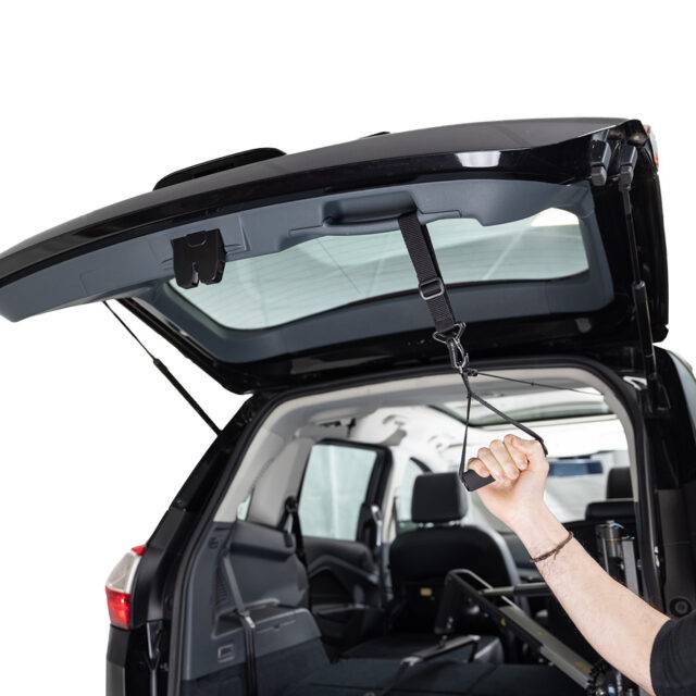 A hand reaching up to grasp a boot closing strap by its soft padded horizontal handle.