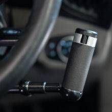 the handle of push pull mechanical hand controls next to the steering wheel in a car. The handle has a switch on the front to control the indicators