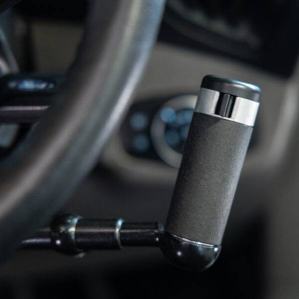 the handle of push pull mechanical hand controls next to the steering wheel in a car. The handle has a switch on the front to control the indicators