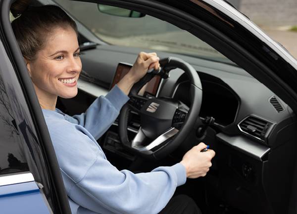 Paralympian Robyn Love sat in the driver's seat of a car holding a Steering Ball and the Hand Controls