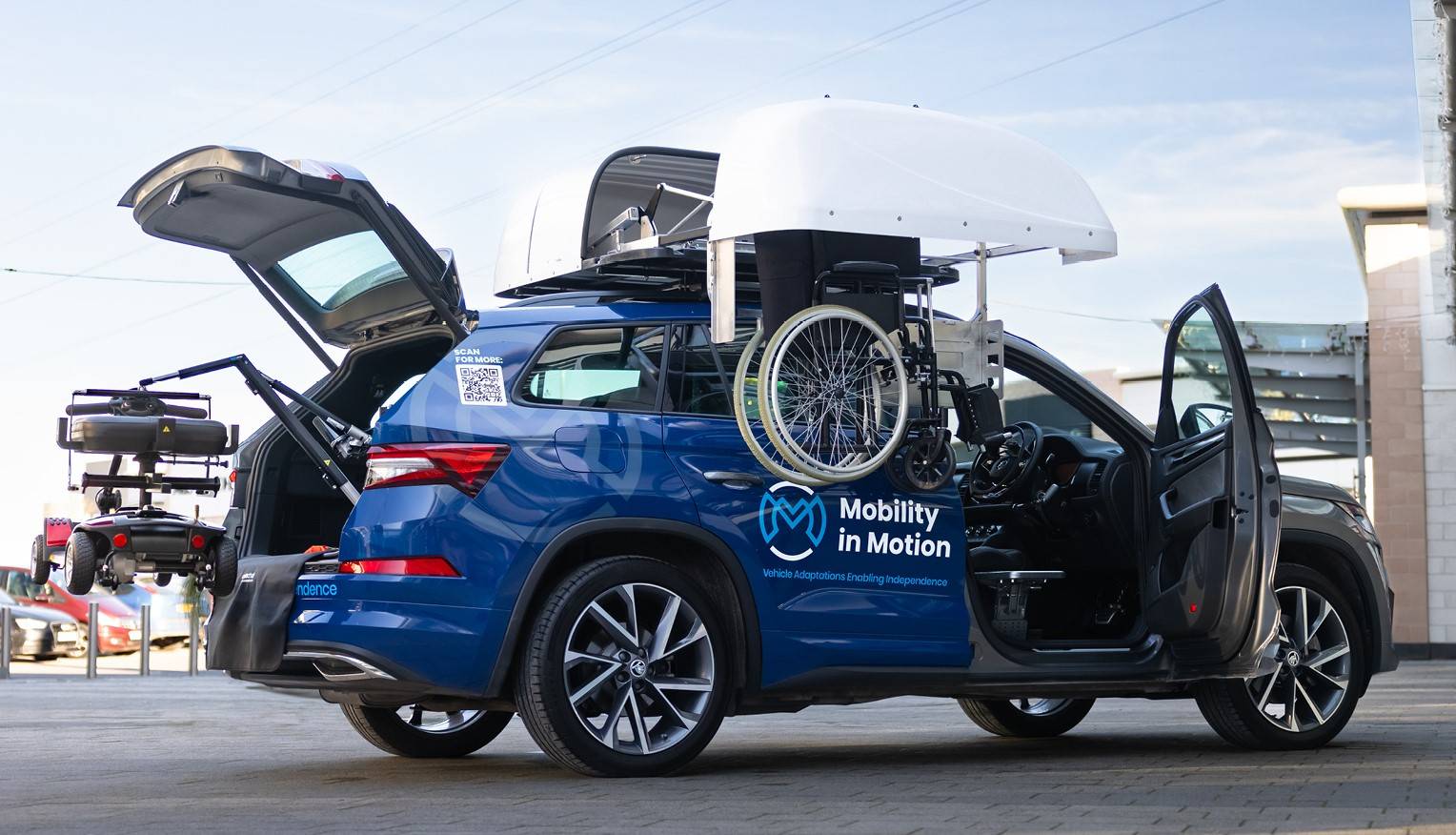 Mobility in Motion demo car with Wheelchair Rooftop Box, a transfer plate on drivers side seat and boot hoist lifting a mobility scooter.