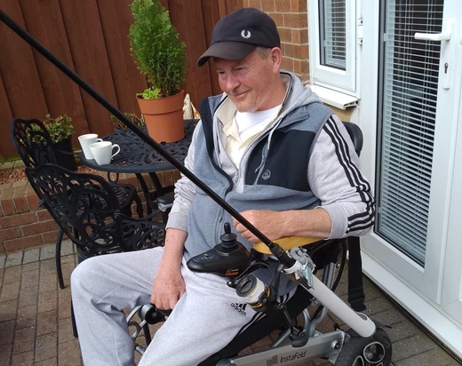 Man sat in powerchair with adapted fishing rod