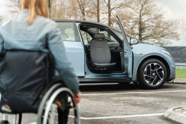 Woman in wheelchair approaching a vehicle equipped with a Turny Manual and Caroseat Flex.
