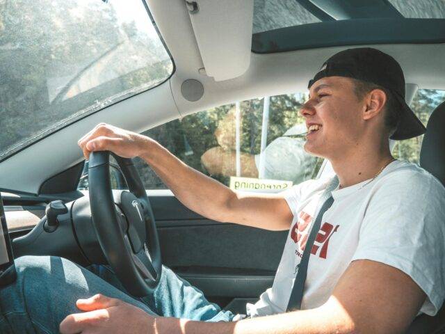 young man in white shirt smiling while driving