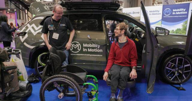 Young wheelchair user trying a swivel seat on the driver's side of Mobility in Motion demo car
