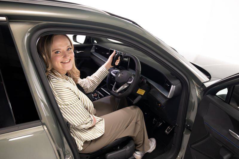 Brand ambassador Nicole Brennan smiling while sat in driver's seat holding a secondary control steering device