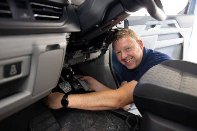 vehicle adaptation installer smiling while fitting pedal adaptations