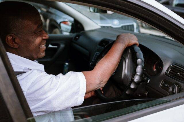 Man smiling while driving Motability car