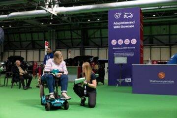 Mobility scooter user speaking with Mobility in Motion team member at Motability Scheme event