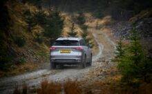 Rear shot of silver JAECOO 8 driving down an off road in scotland