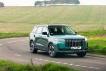 Teal colour JAECOO 5 driving down a country road with green fields