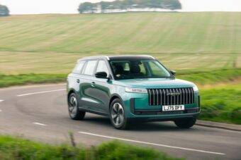 Teal colour JAECOO 5 driving down a country road with green fields